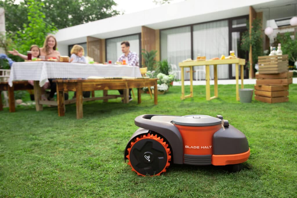Famille profitant sereinement de leur jardin pendant que le robot tondeuse AP Robots travaille en toute sécurité - Technologie de détection avancée permettant une cohabitation sans risque avec enfants et animaux.